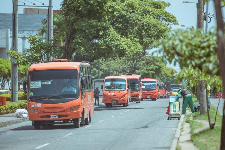 Imagen de una carretera de ibague con busetas naranjas de transporte 